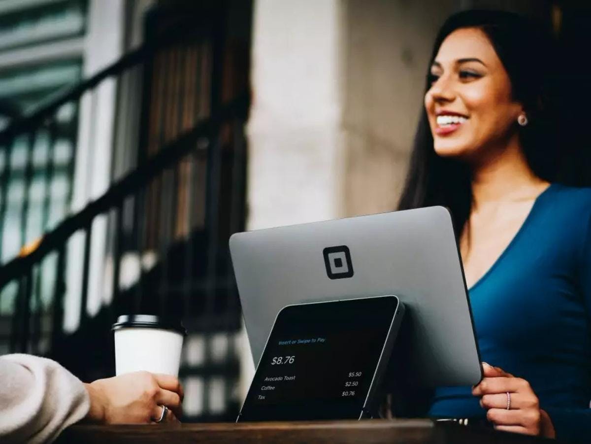 mujer sonriendo en una reunión de trabajo con ordenador y tablet